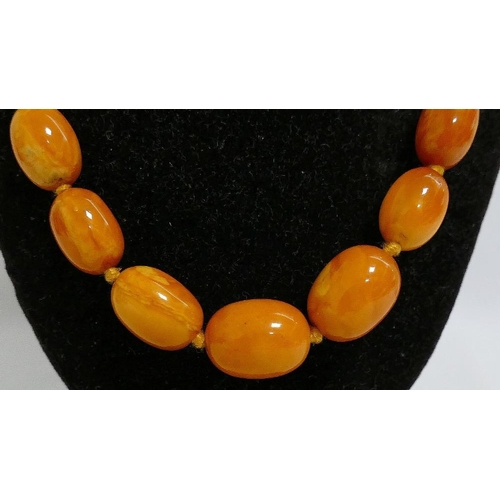 38 - A string of butterscotch amber beads, 69.5cm, the largest bead 1.4cm x 1.9cm, 36.4g gross, a coral b... 