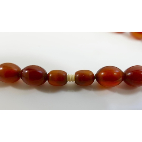 41A - A string of graduated amber coloured beads, possibly Faturan, 63cm long, 61g gross, and a collection... 