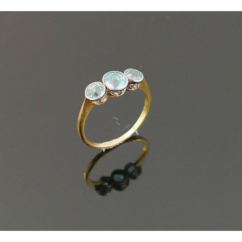 48 - A blue zircon three stone yellow metal ring, the graduated round mixed cut stones in white millegrai... 