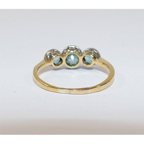 48 - A blue zircon three stone yellow metal ring, the graduated round mixed cut stones in white millegrai... 