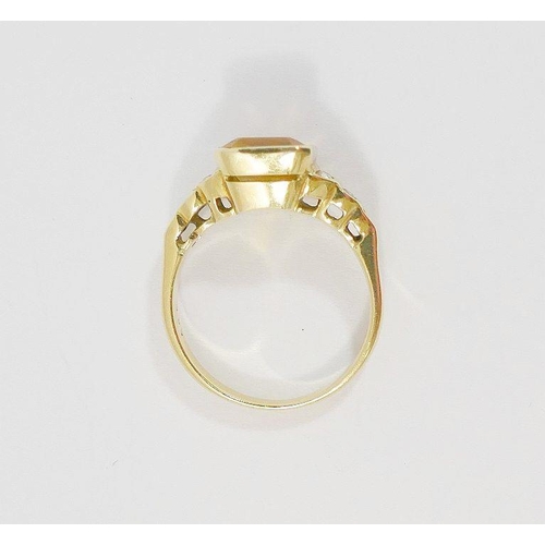 51 - A yellow metal citrine set dress ring, the central emerald-cut stone in rub-over setting, flanked by... 