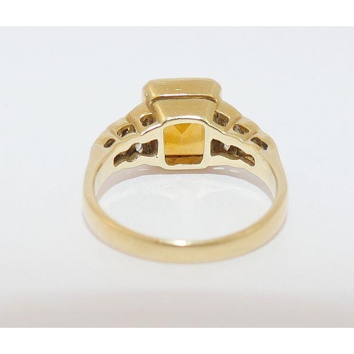 51 - A yellow metal citrine set dress ring, the central emerald-cut stone in rub-over setting, flanked by... 