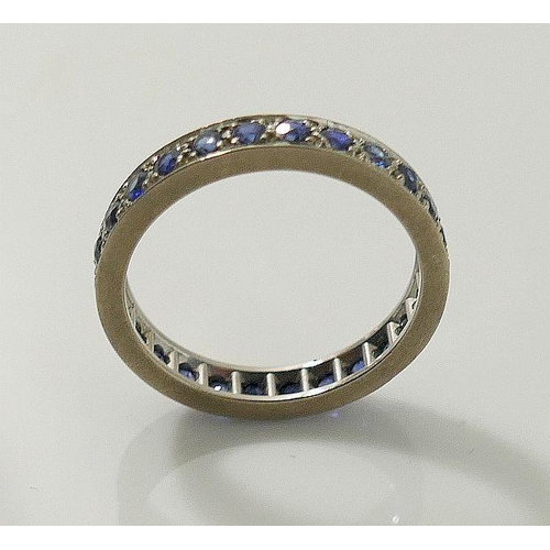 7A - A sapphire eternity ring, set in unmarked white metal, finger size N1/2 3.6g gross