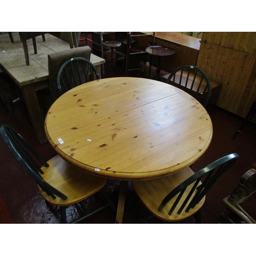 187 - A waxed pine circular extending single pedestal kitchen table together with four spindle back chairs... 