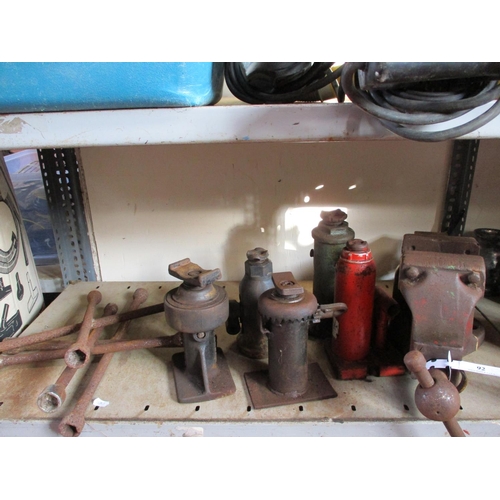 92 - Five vintage bottle jacks, wheel braces and a large vice
