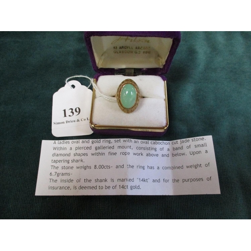 139 - A 14 carat gold pierced ring set with a large oval cabochon jade stone (size O)