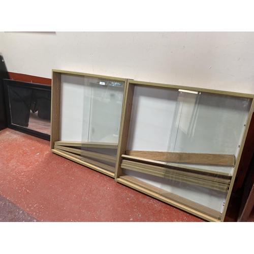 327 - A pair of glazed wall mounted display cabinets together with a dark framed wall mirror