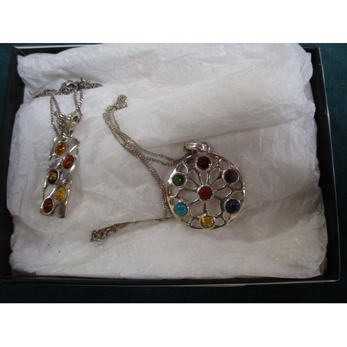 128 - A silver and amber pendant and chain together with a silver pendant and chain set with semi precious