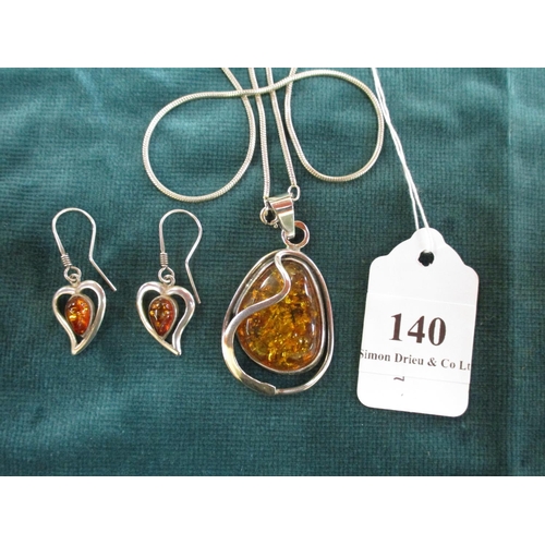 140 - A sterling silver and amber pendant together with a pair of sterling silver and amber earrings