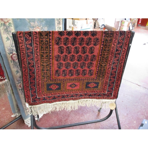 272 - An Afghanistani Belouch 100% wool floor rug on red and black ground (1.4m x 85cm)