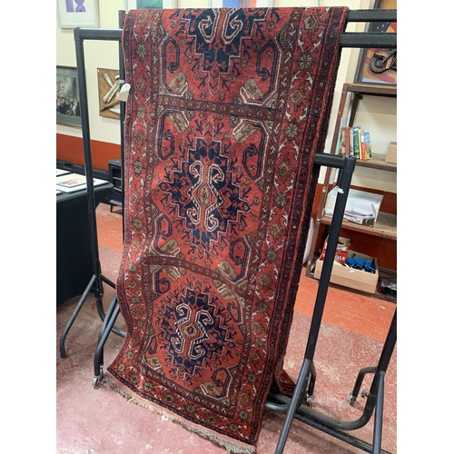 270 - An oriental carpet runner with geometric designs on a red coloured ground