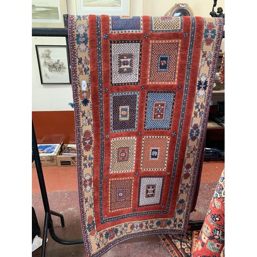 308 - An oriental carpet runner with rectangular designs on a red coloured ground