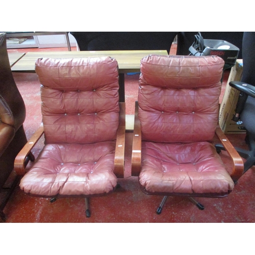 241 - A pair of retro mid twentieth century revolving armchairs upholstered in red and burgundy coloured l... 