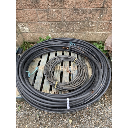 57 - Two coils of black plastic water pipe together with a coil of armoured electric cable