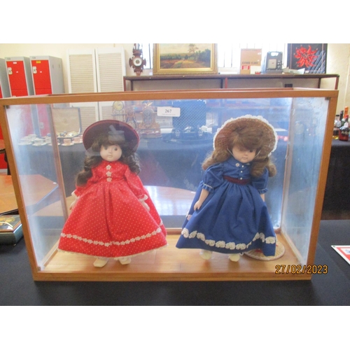 267 - Two porcelain faced dolls in a glass display cabinet