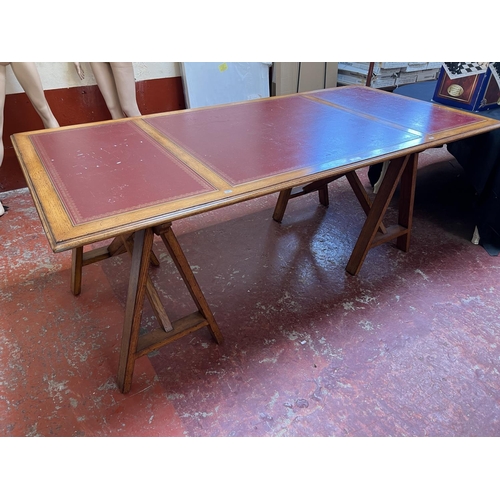 377 - A vintage oak trestle table the top inlaid with red gilded leather and surrounded with brass inlay
a... 