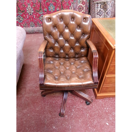 233 - A mahogany revolving office chair upholstered in brown button back leather