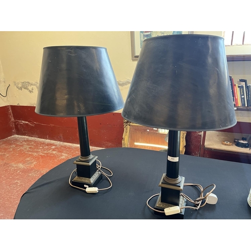 311 - A pair of ebonised and gilded table lamps modelled in the form of pillars on plinths