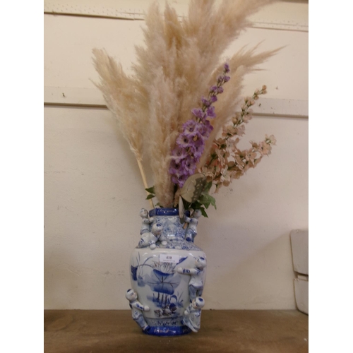 410 - An oriental blue and white vase with figures containing a bouquet of artificial flowers