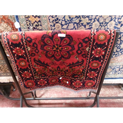 297 - An oriental floor rug decorated with geometric designs on a deep red coloured ground