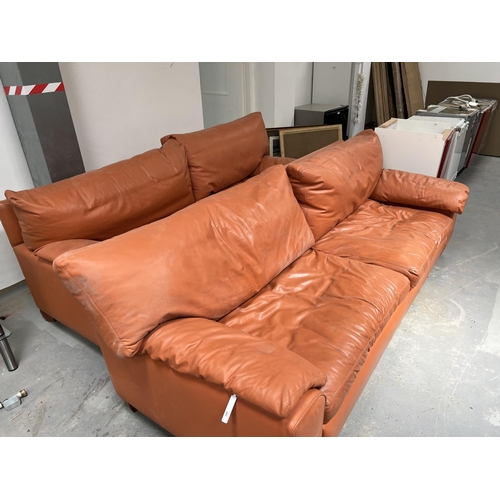 189 - A pair of three seater couches and a matching footstool upholstered in terracotta coloured leather