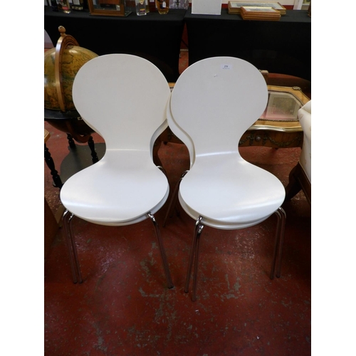 275 - A set of four white coloured stacking dining chairs set upon chrome legs