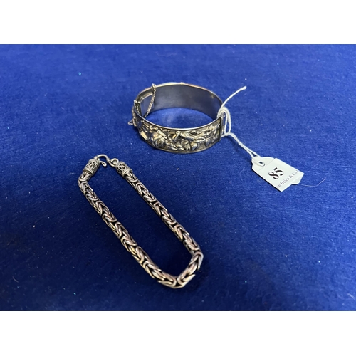 85 - A silver bangle with foliate decoration together with a silver fox tail bracelet