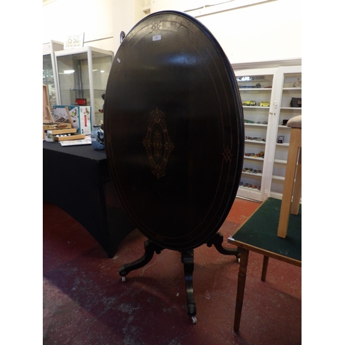 243 - A nineteenth century ebonised mahogany tilt top oval breakfast table with marquetry inlay and gilded... 