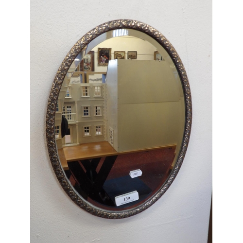 139 - An oval bevelled wall mirror in silver gilt frame