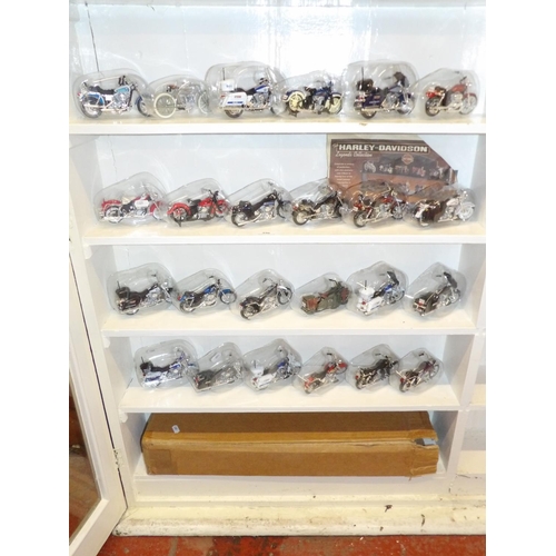 396 - A collection of twenty four Harley Davidson Legends collection motorcycle models complete with displ... 