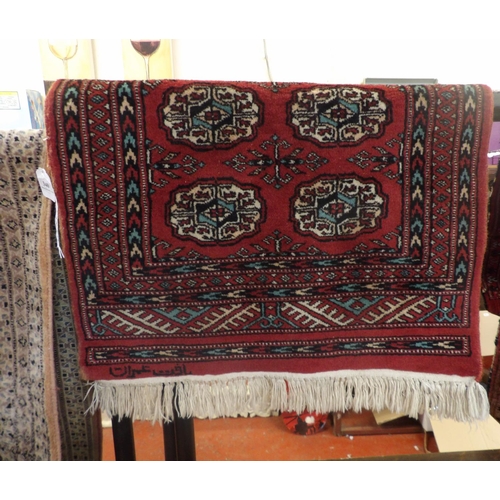 340 - An oriental floor rug decorated with geometric designs on a red ground