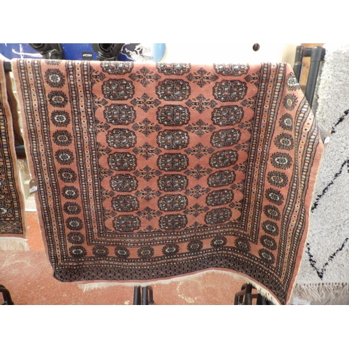 293 - An oriental floor rug decorated with geometric designs on a pink coloured ground