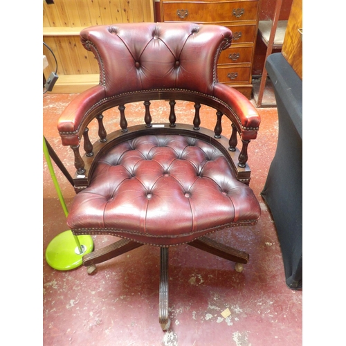 316 - A revolving mahogany office chair upholstered in burgundy coloured leather