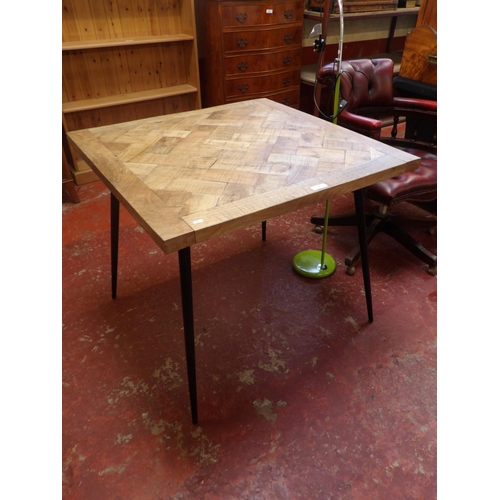 319 - A hard wood table with parquet design top and set upon black tapered legs