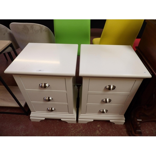 410 - A pair of three drawer bedside chests finished in off white