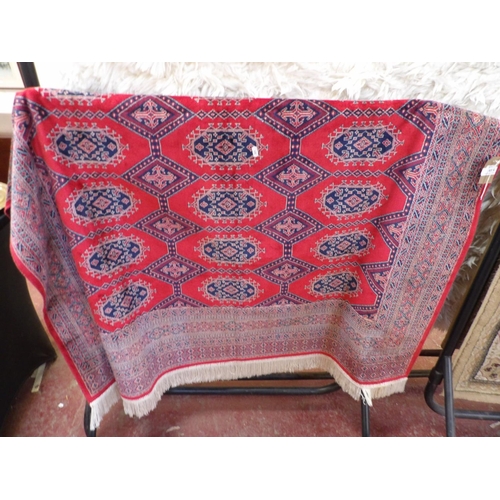 418 - An oriental floor rug decorated with geometric designs on a red coloured ground