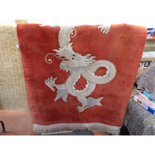 419 - A Quyam 100% wool floor rug with a dragon design on a burnt red coloured ground