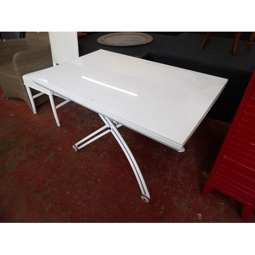 295 - A contemporary white finished and wheeled extending table with fold over rotating top