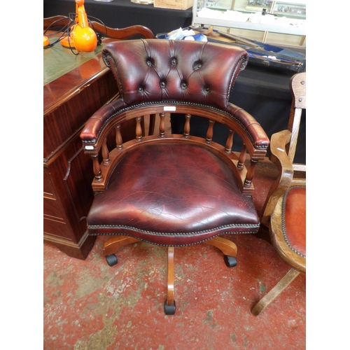 303 - A revolving office chair upholstered in burgundy coloured leather