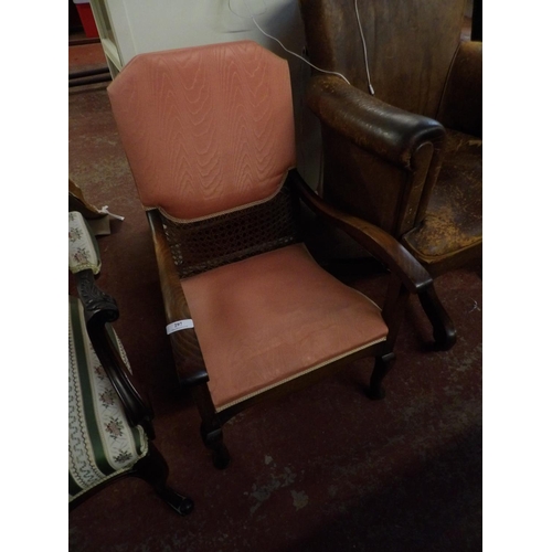 297 - A turn of the twentieth century oak open armchair with caned decoration and upholstered in pink colo... 