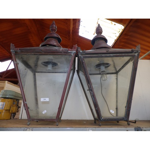 116 - A pair of wrought metal lantern wall brackets together with the lanterns