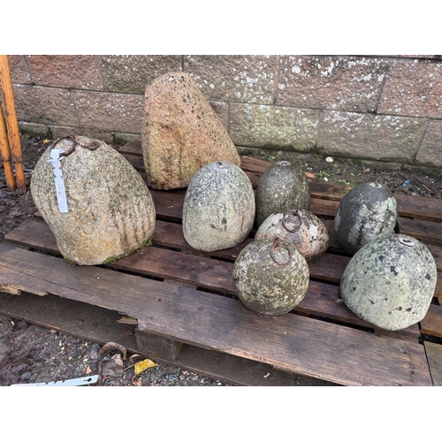 51 - A collection of seven vintage Jersey granite corn weights together with a coach stone