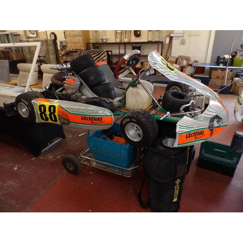 100 - Two racing go-karts each mounted upon a service trolley together with various sets of wheels, spares... 