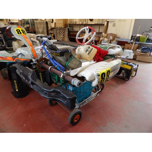 100 - Two racing go-karts each mounted upon a service trolley together with various sets of wheels, spares... 