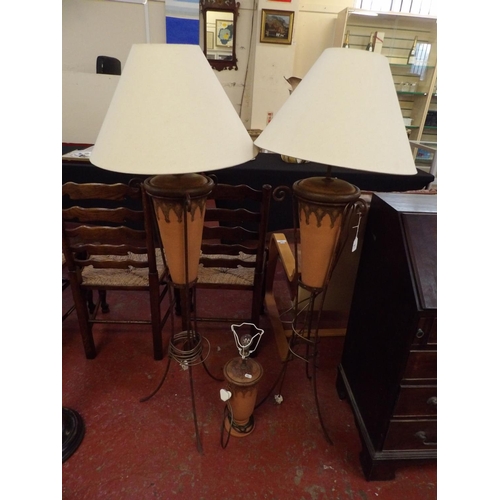 261 - A pair of floor standing wrought metal and terracotta lamps together with a matching table lamp