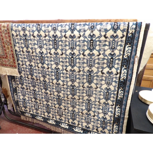 389 - A Tunisian hand knotted floor rug decorated with blue geometric designs on a neutral coloured ground... 