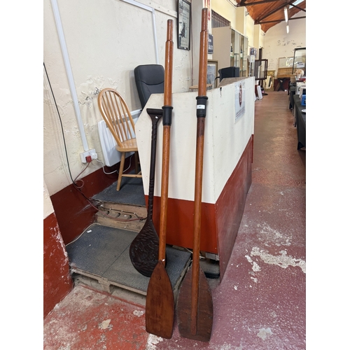 187 - A pair of vintage wooden oars together with a hard wood tribal paddle