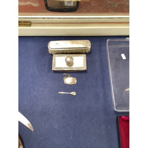 385 - Four pieces of silver ware to include a desk blotter, a dressing table brush, a Port decanter label ... 