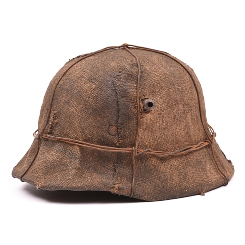 75 - A German M16 style steel helmet,  with glued on WWII style hessian covering, iron wire binding, and ... 