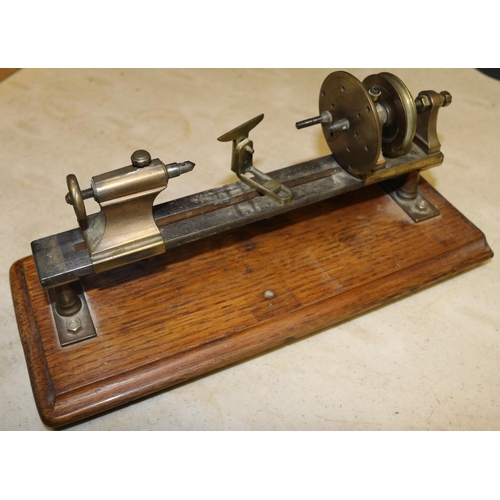 46 - A small brass model of a basic wood turning lathe. Mounted on a hardwood plinth. Intended to be a st... 